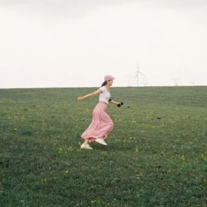 Jeune femme courant dans un champ avec des éoliennes en arrière-plan