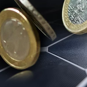 Pièces de monnaie sur un panneau solaire illustrant les tarifs de rachat photovoltaïque