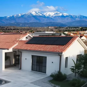 Installation de panneaux solaires sur le toit d'une maison à Perpignan, avec le massif du Canigou enneigé en arrière-plan