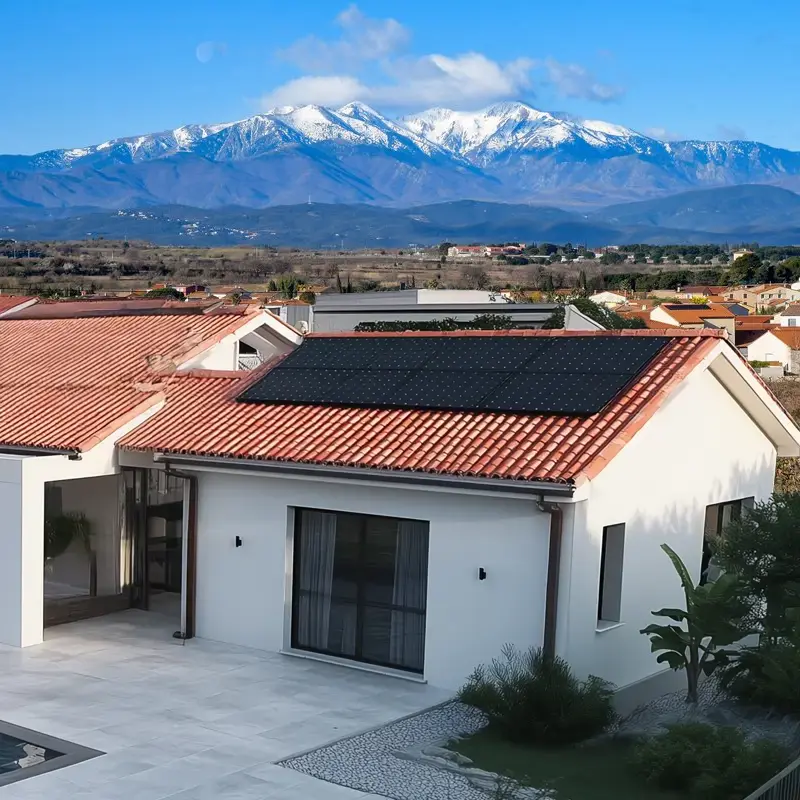 Installation de panneaux solaires sur le toit d'une maison à Perpignan, avec le massif du Canigou enneigé en arrière-plan